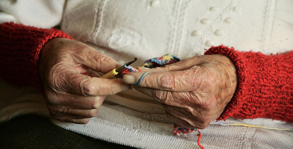 Nahaufnahme der Hände einer Seniorin, die im Rahmen einer freiwilligen Tätigkeit in einem chilenischen Heim betreut wird.