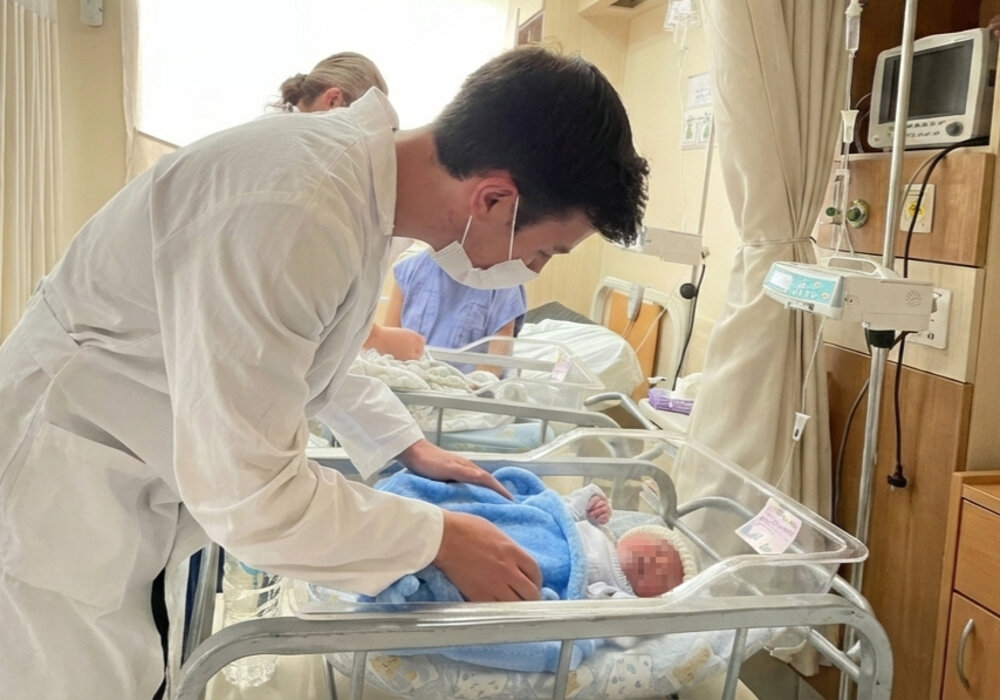 Ein Freiwilliger kümmert sich in einem Krankenhaus in Ecuador liebevoll um einen Säugling.